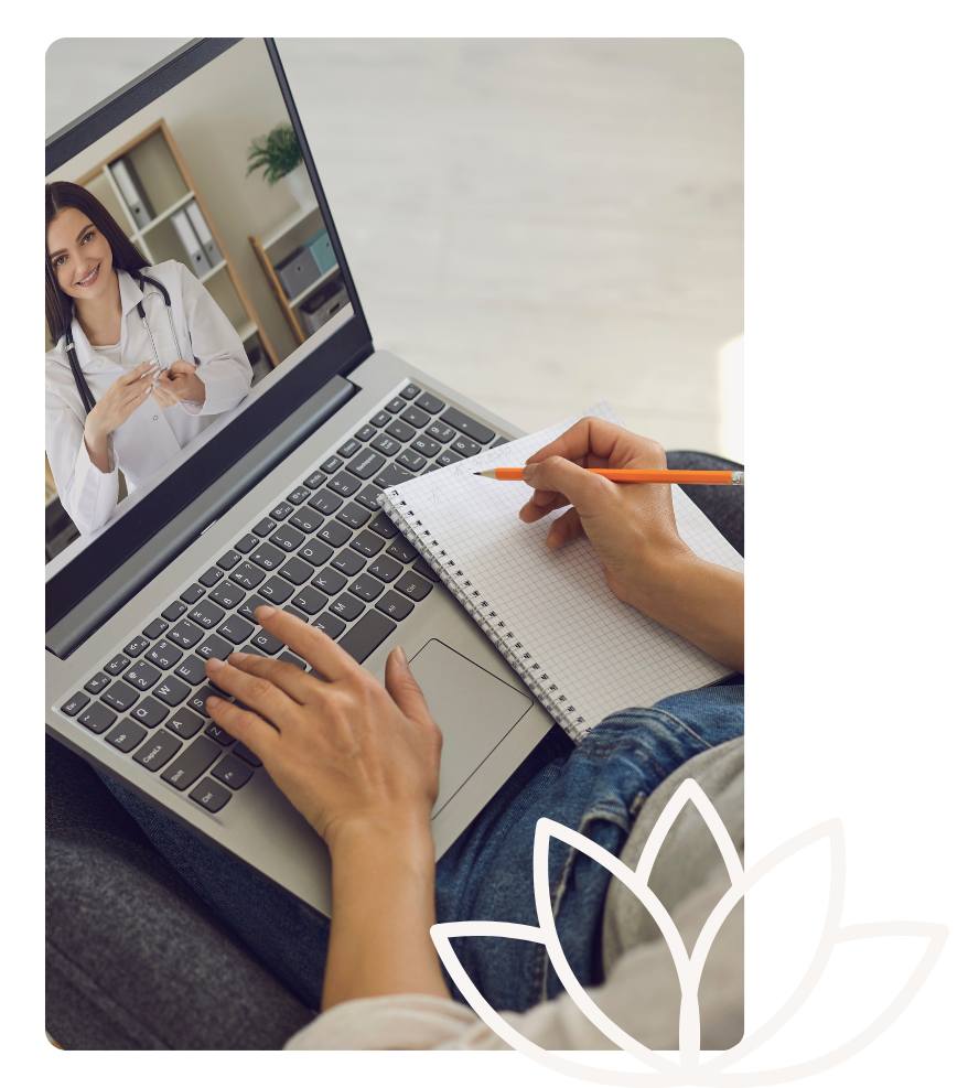 A patient takes notes during a virtual appointment with a female healthcare provider, speaking over secure video chat from the comfort of home.